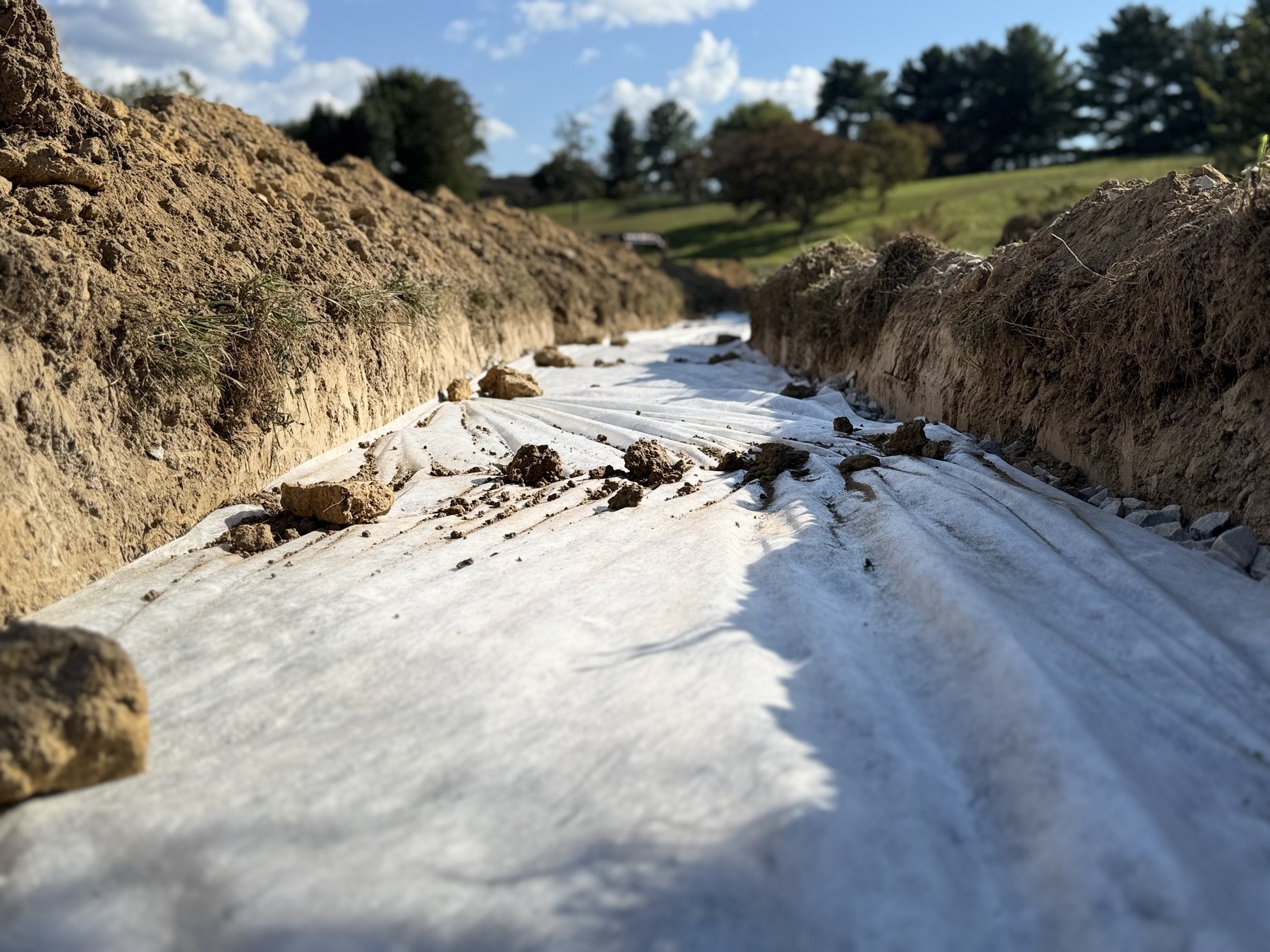 Drain field trench prepared with fabric and aggregate for septic field lines.