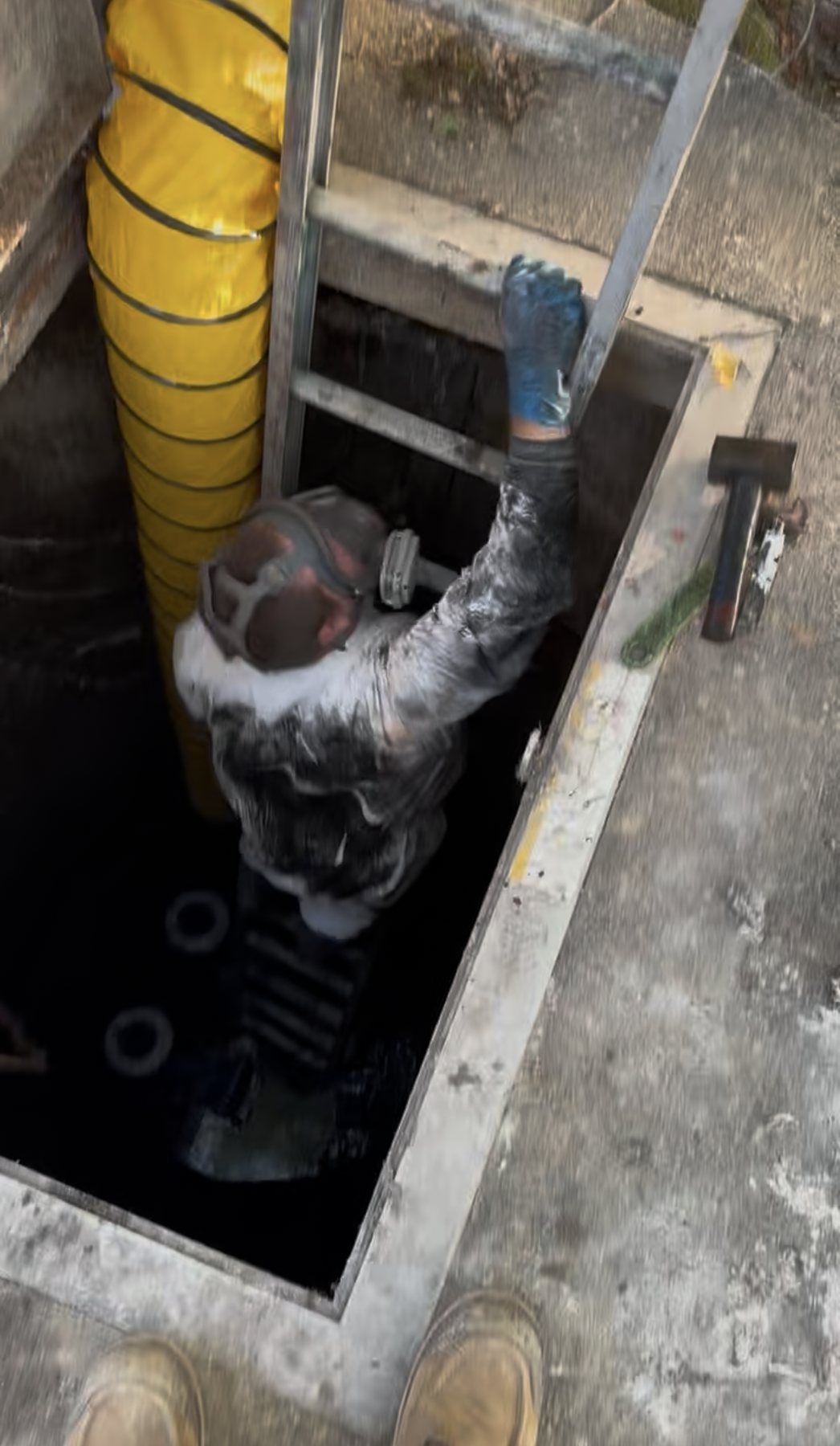 Municipal sewer access work with a technician inside a utility opening.