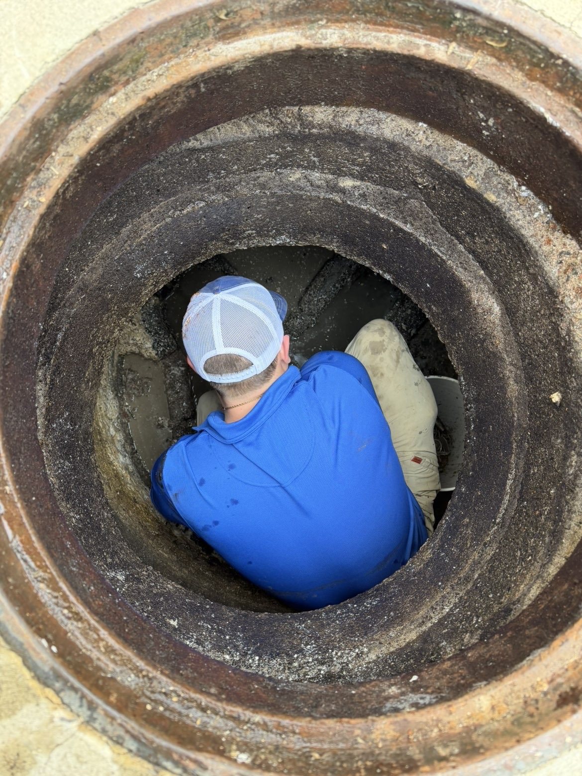 Technician inspecting an open septic access point during a septic inspection.