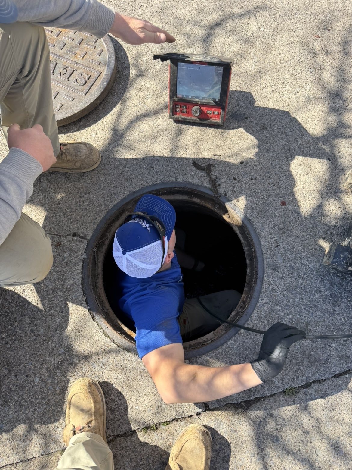 Star Septic technician inspecting an open septic access point with camera equipment.