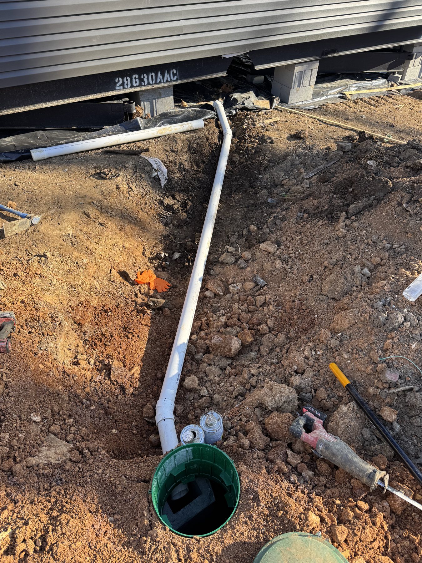 Excavated utility line running from a home toward a septic access point.